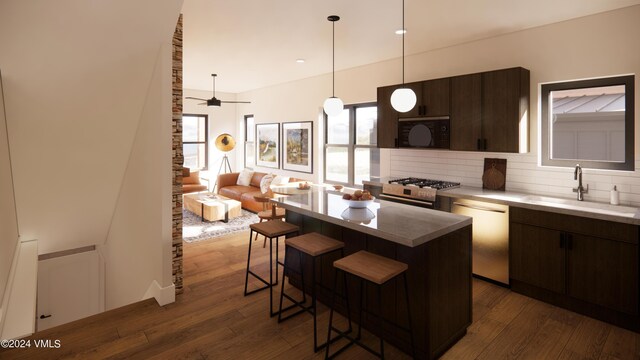 kitchen featuring a kitchen bar, sink, dark brown cabinets, appliances with stainless steel finishes, and a kitchen island