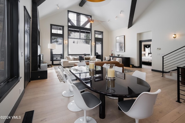 dining space with high vaulted ceiling, light wood-style flooring, visible vents, stairs, and beamed ceiling