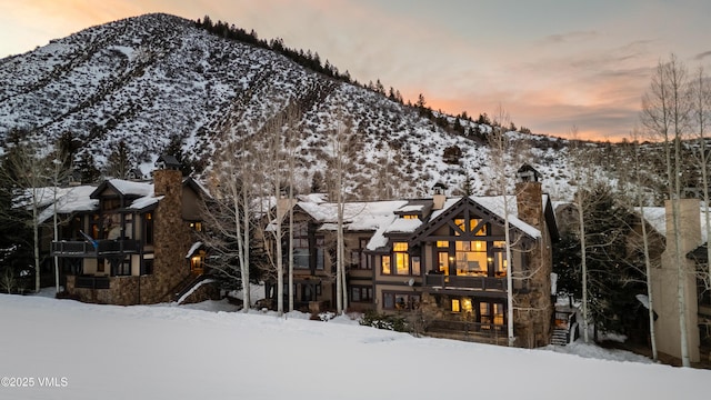 view of front of property featuring stone siding, a chimney, and a mountain view