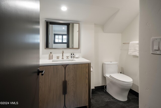 bathroom featuring toilet, vanity, and baseboards