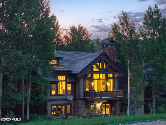 352 Cresta Rd, Edwards, CO 81632 - back of house at dusk with a chimney, stone siding, and a balcony