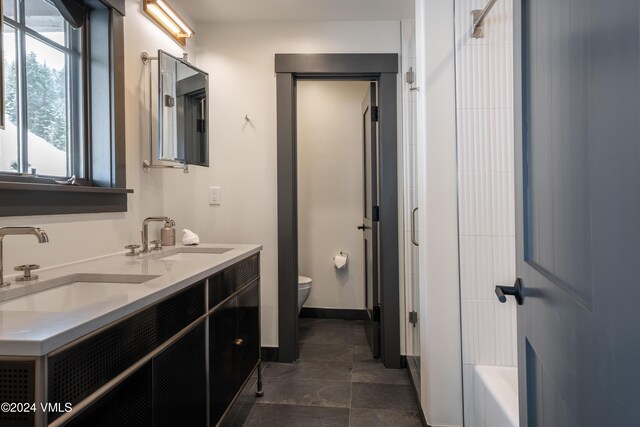 bathroom with toilet, double vanity, a shower, and a sink