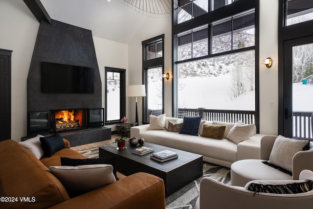 living area with plenty of natural light, a fireplace, and a towering ceiling