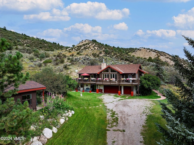 407 Meadow Rd, Edwards, CO 81632 - view of front of property with gravel driveway, a deck with mountain view, a front yard, an attached garage, and a chimney