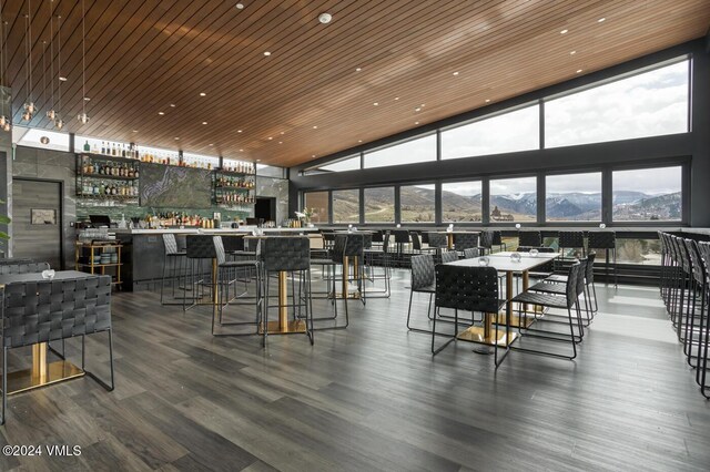 dining space featuring wood ceiling, bar, wood-type flooring, expansive windows, and a mountain view