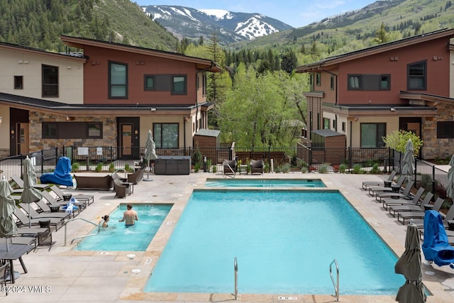 view of pool featuring a hot tub, a patio, a mountain view, and pool water feature