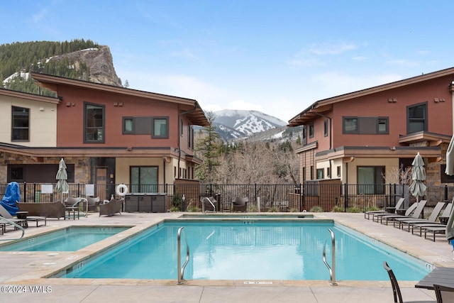 view of pool with a hot tub, a patio, and a mountain view