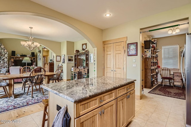 1987 Eagle Ranch Rd, Eagle, CO 81631 - kitchen with arched walkways, a chandelier, light stone countertops, pendant lighting, and light tile patterned floors