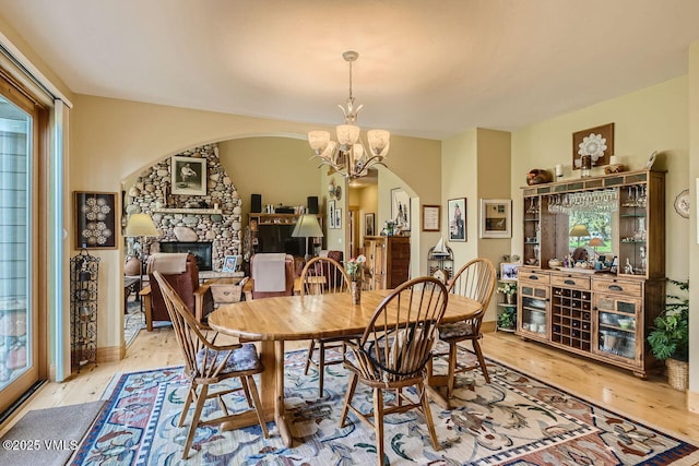 1987 Eagle Ranch Rd, Eagle, CO 81631 - dining space with arched walkways, a fireplace, light wood finished floors, and a chandelier