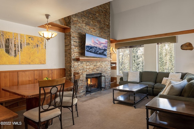 carpeted living room with a stone fireplace and a high ceiling