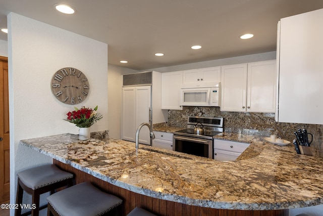 kitchen featuring sink, white cabinetry, decorative backsplash, stainless steel range with electric cooktop, and kitchen peninsula