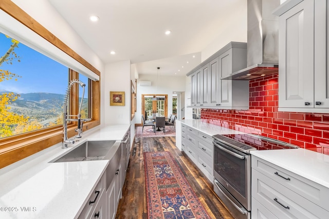 kitchen with wall chimney range hood, backsplash, dark hardwood / wood-style flooring, gray cabinets, and stainless steel electric stove