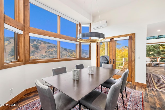 dining room featuring a wall unit AC, hardwood / wood-style floors, and a high ceiling