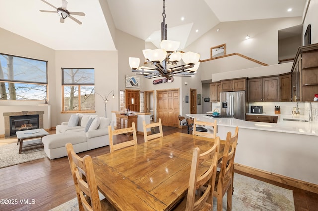 2960 June Creek Trl Unit A, Avon, CO 81620 - dining room with a chandelier, light wood-type flooring, high vaulted ceiling, a fireplace, and ceiling fan