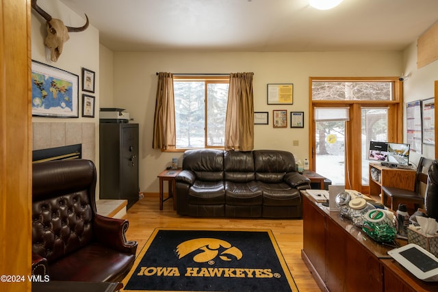 living room with a tiled fireplace and light hardwood / wood-style flooring