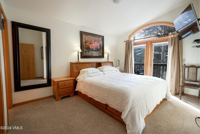 carpeted bedroom featuring lofted ceiling and access to exterior