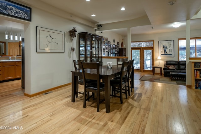 dining space with sink, light hardwood / wood-style floors, and french doors