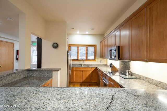 kitchen with sink, light stone countertops, a healthy amount of sunlight, and appliances with stainless steel finishes