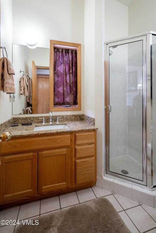 bathroom featuring tile patterned flooring, a shower with door, and sink