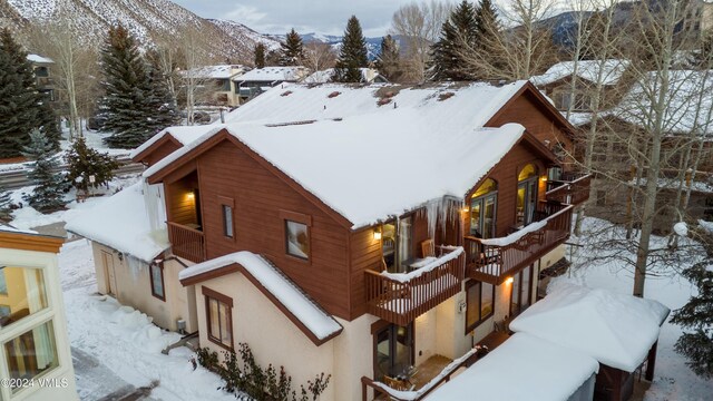 snow covered property with a balcony and a mountain view