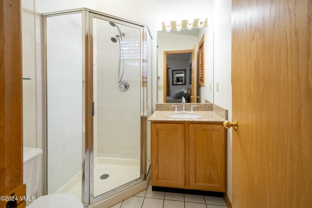 bathroom with tile patterned flooring, walk in shower, vanity, and toilet