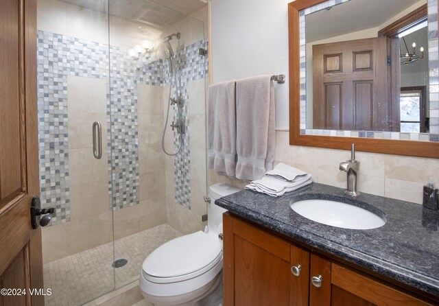 bathroom featuring tile walls, decorative backsplash, vanity, walk in shower, and toilet