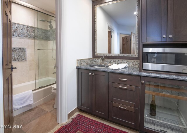 full bathroom with tasteful backsplash, vanity, combined bath / shower with glass door, and toilet