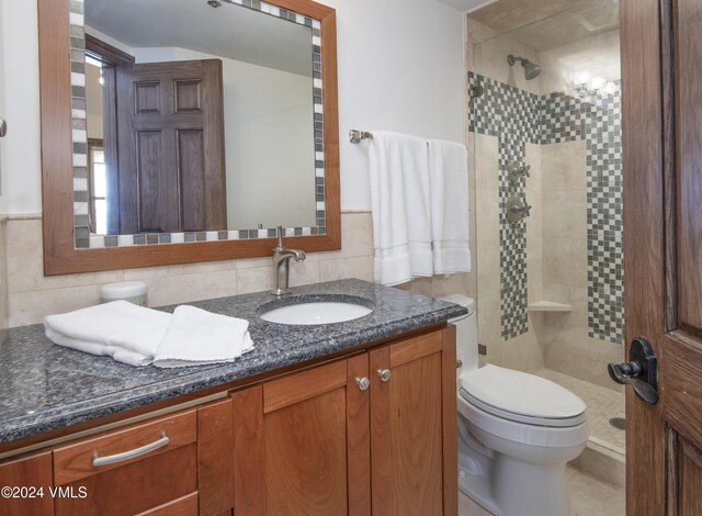 bathroom featuring vanity, toilet, a shower with shower door, and tile walls