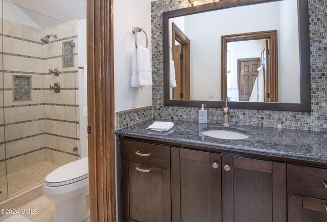 bathroom with toilet, tasteful backsplash, vanity, a shower with door, and tile patterned flooring