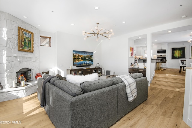 living room featuring a notable chandelier, light hardwood / wood-style flooring, and a fireplace