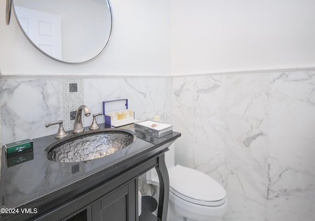 bathroom with vanity, tile walls, and toilet