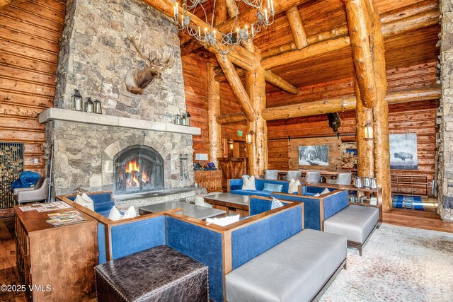 living room featuring hardwood / wood-style flooring, high vaulted ceiling, a stone fireplace, wooden ceiling, and beamed ceiling