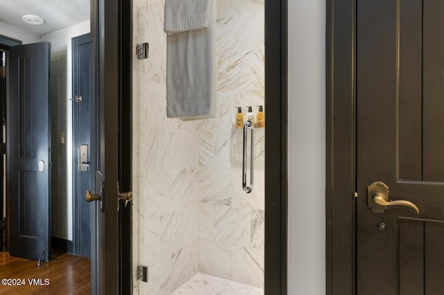 bathroom with tiled shower and hardwood / wood-style floors