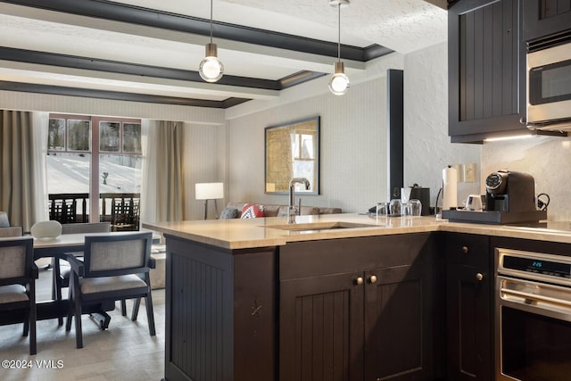 kitchen featuring appliances with stainless steel finishes, beam ceiling, sink, and hanging light fixtures