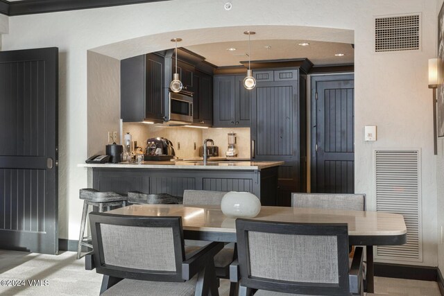 kitchen with decorative light fixtures, sink, a kitchen bar, decorative backsplash, and kitchen peninsula