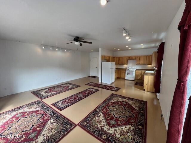 interior space with white appliances, track lighting, kitchen peninsula, and ceiling fan