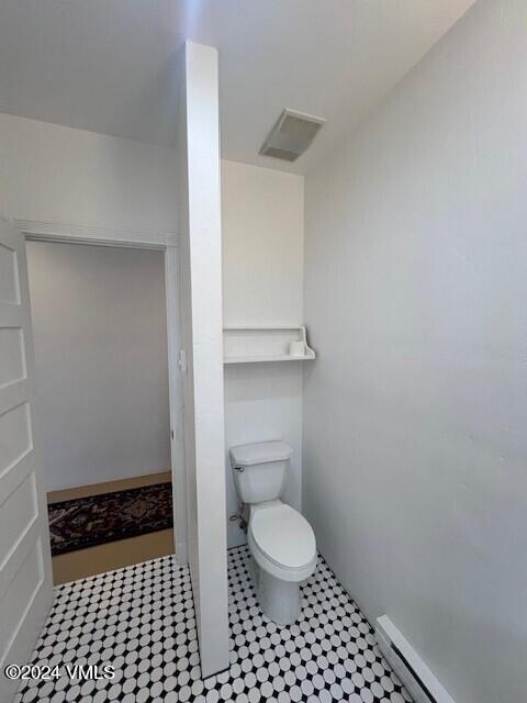 bathroom with a baseboard heating unit and toilet