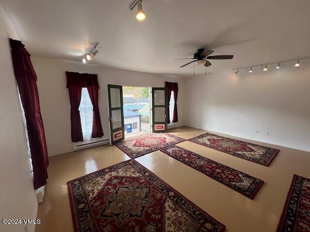 interior space with ceiling fan, track lighting, and a baseboard heating unit