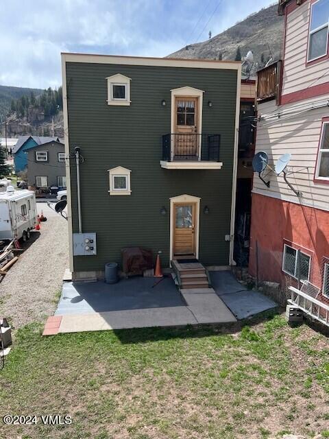 back of house featuring a balcony, a lawn, and a patio area