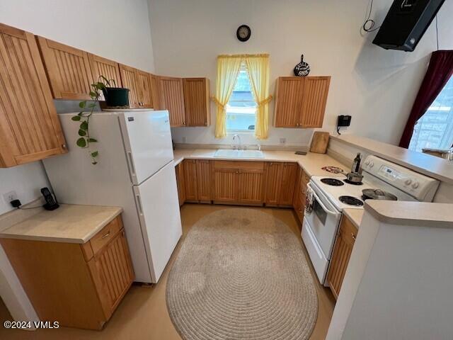 kitchen with sink, white appliances, and kitchen peninsula