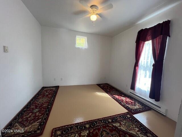 empty room featuring ceiling fan and a baseboard radiator