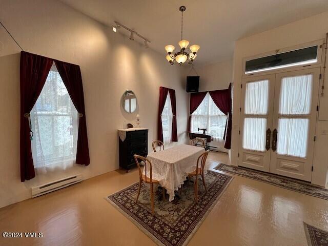 dining room with french doors, a baseboard radiator, rail lighting, and a notable chandelier