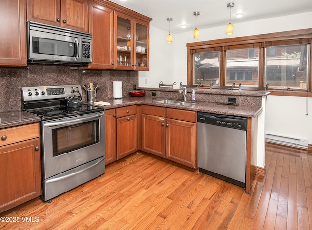 83 Larkspur Ln Unit A, Avon, CO 81620 - kitchen with appliances with stainless steel finishes, a baseboard heating unit, brown cabinetry, and light wood-style floors