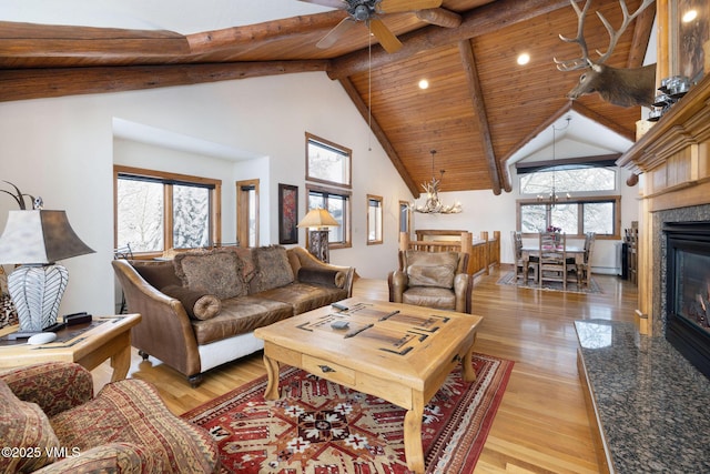 living room featuring a high end fireplace, beam ceiling, light hardwood / wood-style flooring, and wooden ceiling