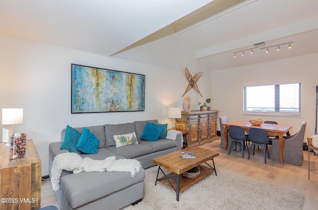 living room featuring rail lighting, hardwood / wood-style floors, and beam ceiling