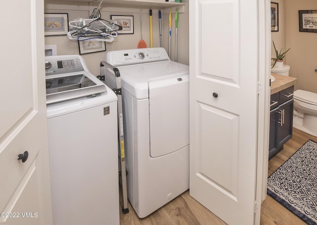 clothes washing area with washing machine and dryer, light wood-style flooring, and laundry area