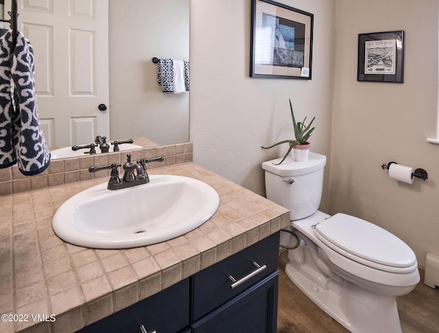 half bath featuring vanity, toilet, and wood finished floors