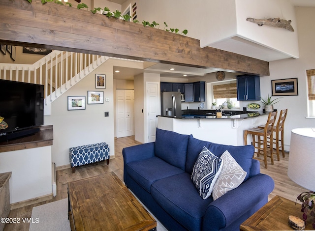 living area featuring light wood finished floors, baseboards, stairs, beam ceiling, and recessed lighting