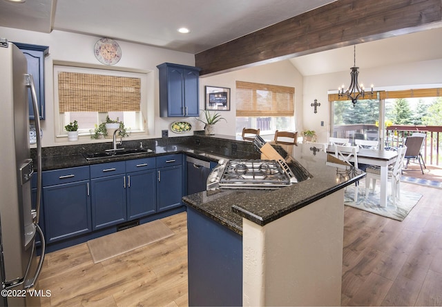 kitchen featuring a peninsula, blue cabinetry, appliances with stainless steel finishes, and a sink