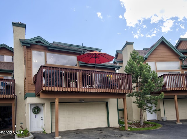 view of front of property with stucco siding, an attached garage, aphalt driveway, and a chimney